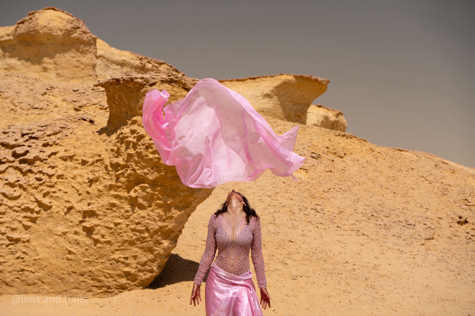 Pink silk veil caught by the wind above a dancer in the white desert