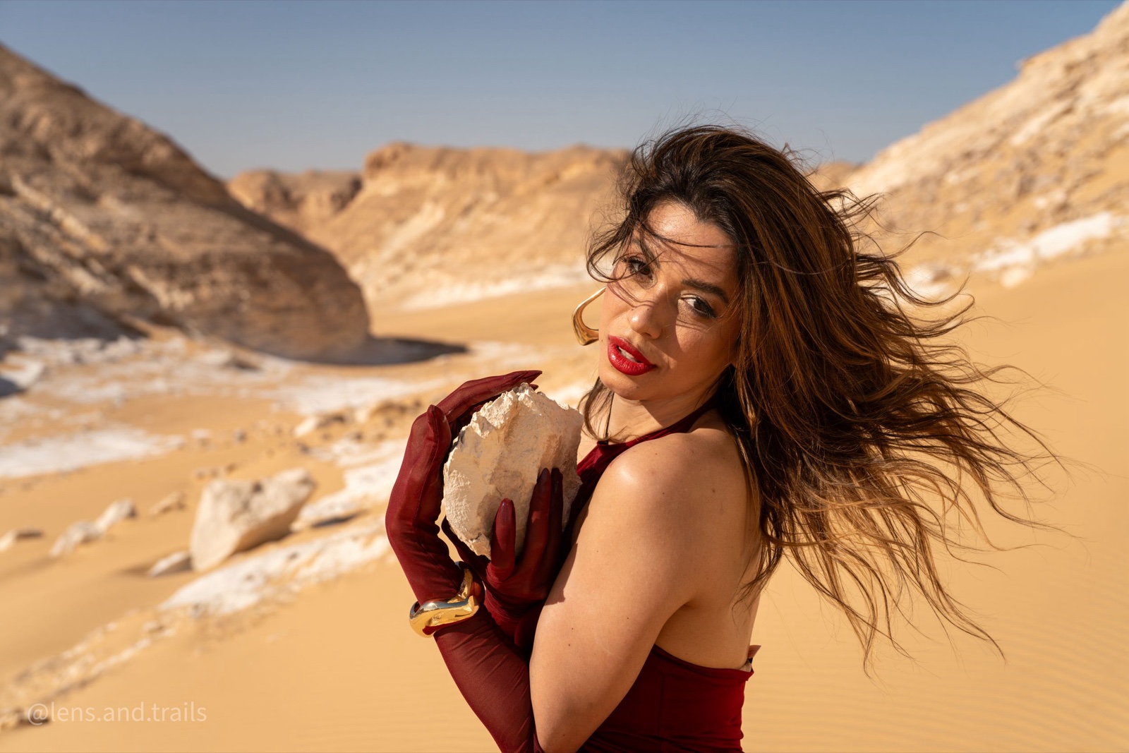 Woman in crimson holding a quartz crystal in the white desert