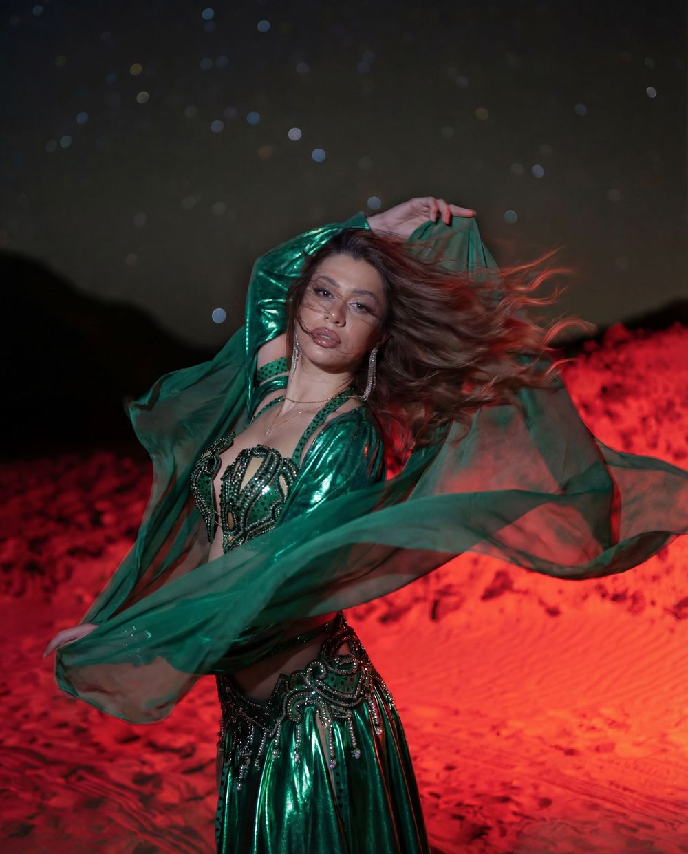 Dancer in emerald silk in the desert at night beneath the stars
