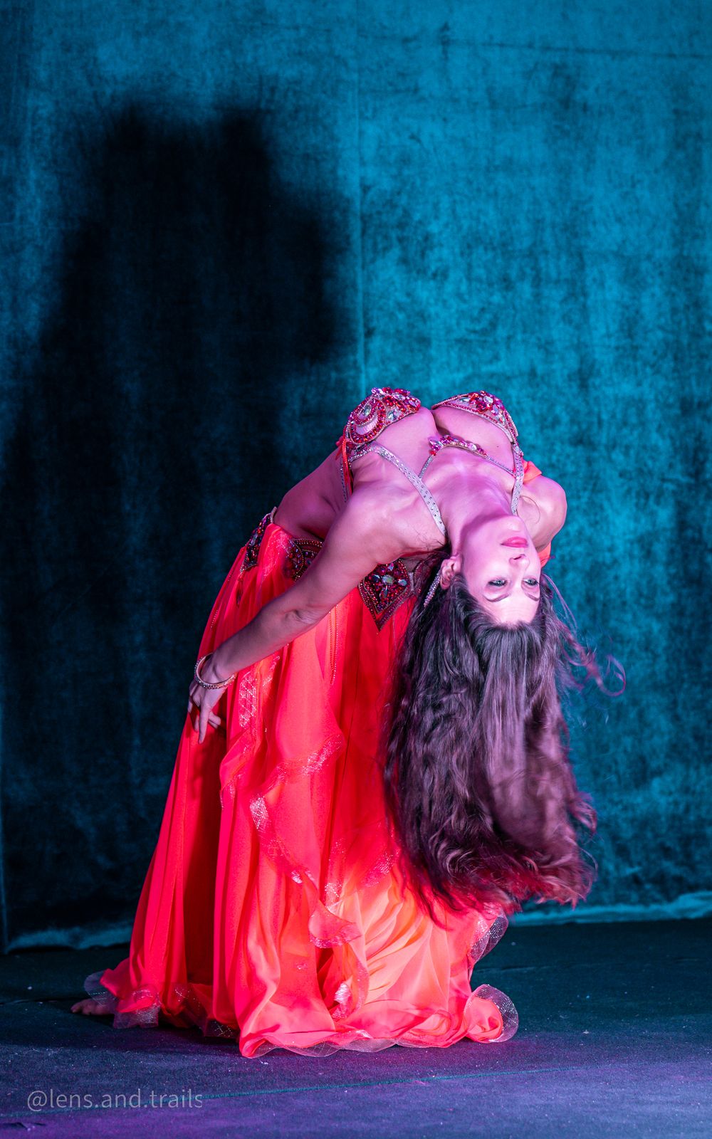 Bellydancer arching backward on a blue-lit stage